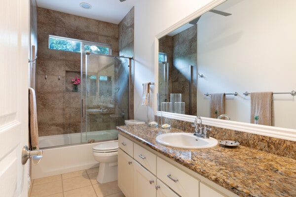 full bathroom with tile patterned flooring, enclosed tub / shower combo, toilet, and vanity