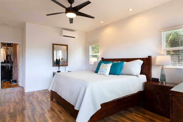 bedroom featuring ceiling fan, a wall mounted air conditioner, wood finished floors, a closet, and a spacious closet