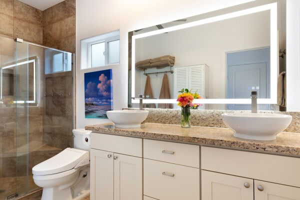 full bath with a sink, a stall shower, and double vanity