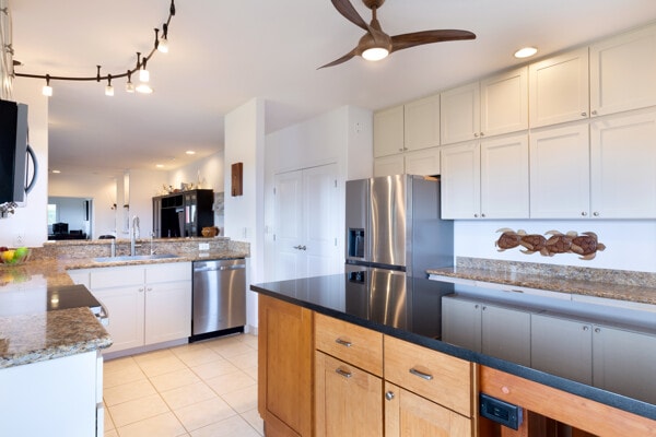 kitchen featuring white cabinets, appliances with stainless steel finishes, a sink, dark stone countertops, and a ceiling fan
