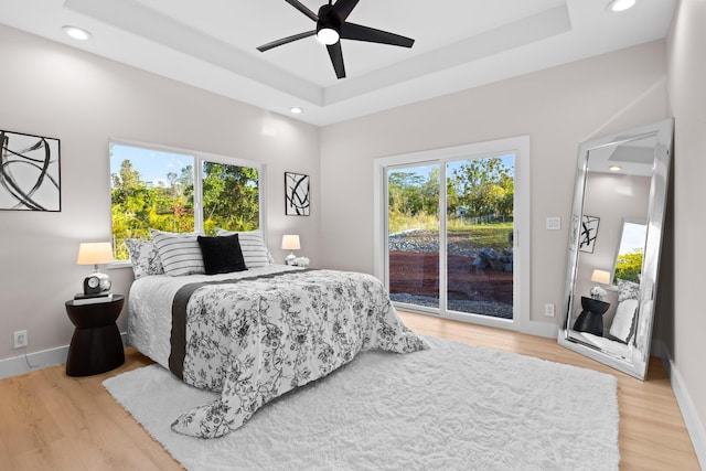 bedroom with access to outside, a raised ceiling, light wood-style flooring, baseboards, and recessed lighting