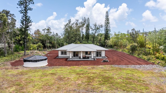 view of front facade featuring a patio, a front lawn, and a wooded view