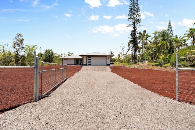 view of front of property with gravel driveway, a gate, a garage, and metal roof