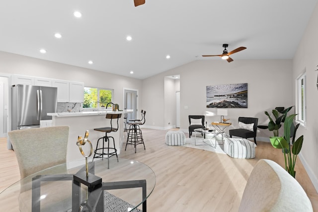 living room featuring light wood-style floors, a ceiling fan, baseboards, recessed lighting, and lofted ceiling