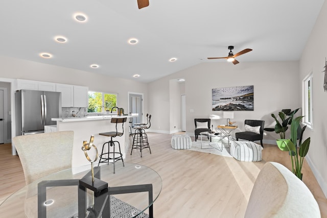 dining space with a ceiling fan, light wood-style flooring, baseboards, vaulted ceiling, and recessed lighting