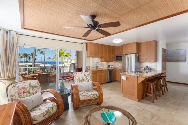 kitchen featuring ceiling fan, tasteful backsplash, appliances with stainless steel finishes, and a kitchen bar