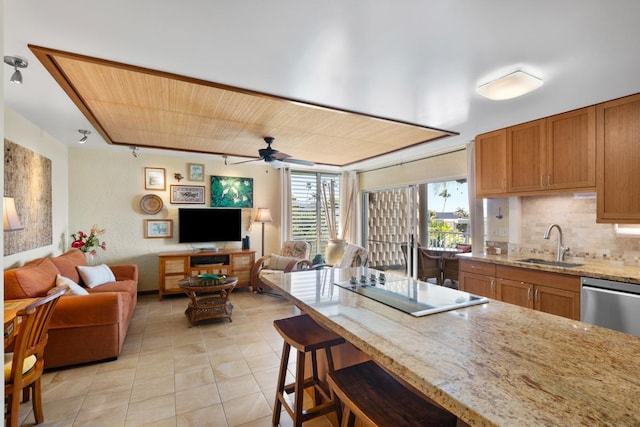 kitchen featuring a ceiling fan, a sink, open floor plan, decorative backsplash, and light tile patterned flooring