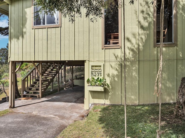 view of property exterior featuring a carport, concrete driveway, and stairway