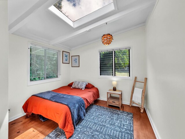 bedroom with wood finished floors, a skylight, and baseboards