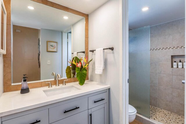 bathroom featuring vanity, toilet, recessed lighting, and tiled shower