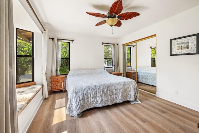 bedroom featuring baseboards, light wood-style flooring, ceiling fan, and a closet