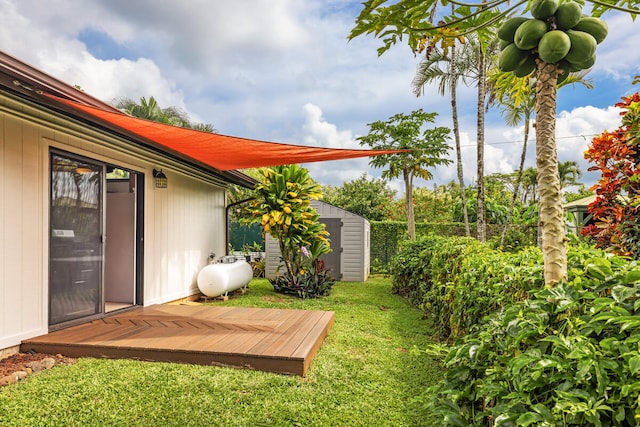 view of yard featuring a wooden deck, fence, an outbuilding, and a shed