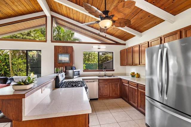kitchen featuring vaulted ceiling with beams, light countertops, a sink, light tile patterned floors, and stainless steel appliances