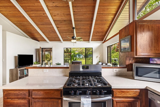 kitchen with light countertops, appliances with stainless steel finishes, and vaulted ceiling with beams