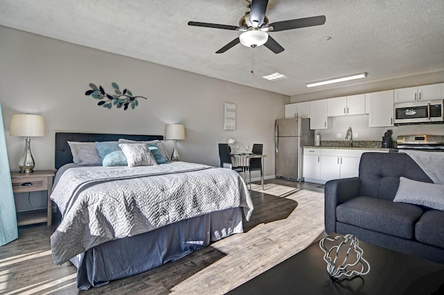355 Kalanianaole St Unit 225, Hilo, HI 96720 - bedroom with freestanding refrigerator, a textured ceiling, a sink, and light wood-type flooring