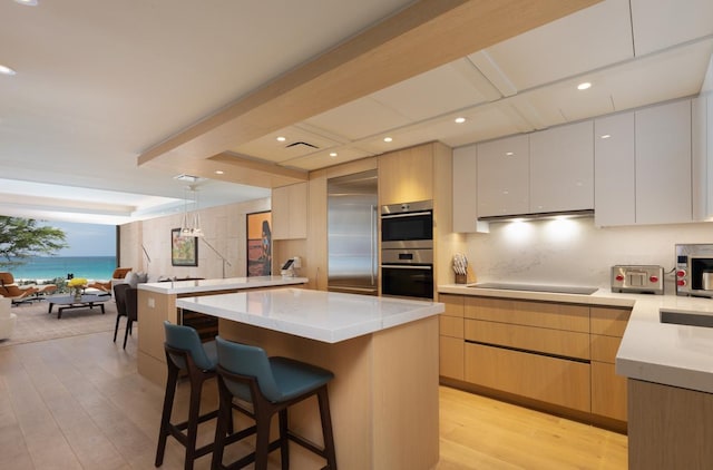 66-84 Kaunaoa Dr Unit A21, Kamuela, HI 96743 - kitchen with stainless steel appliances, light wood-type flooring, modern cabinets, a breakfast bar, and beam ceiling