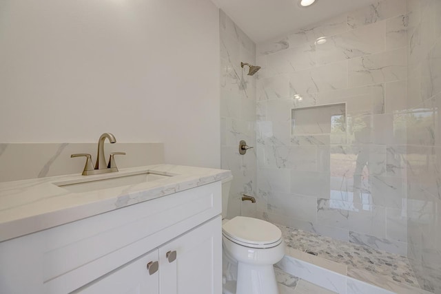 bathroom with vanity, toilet, marble finish floor, recessed lighting, and tiled shower