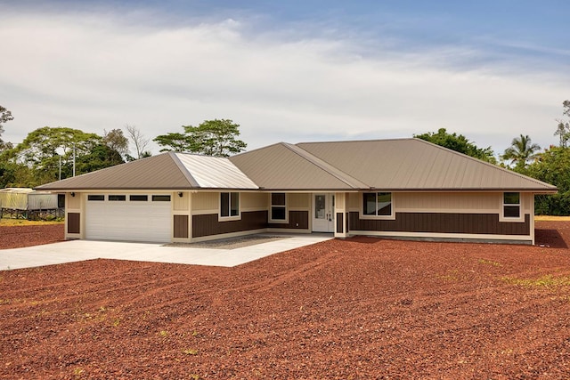 ranch-style house with an attached garage, driveway, and metal roof