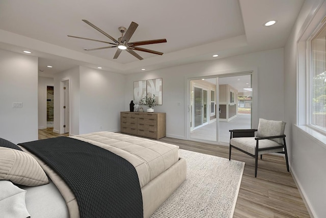 bedroom with baseboards, recessed lighting, a tray ceiling, and light wood-style flooring