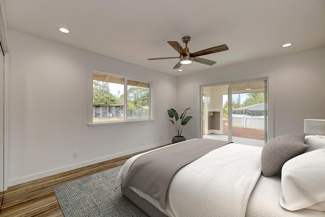 bedroom with access to outside, baseboards, wood finished floors, and multiple windows