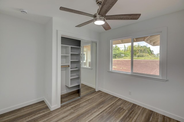 unfurnished bedroom with a ceiling fan, baseboards, wood finished floors, and a closet