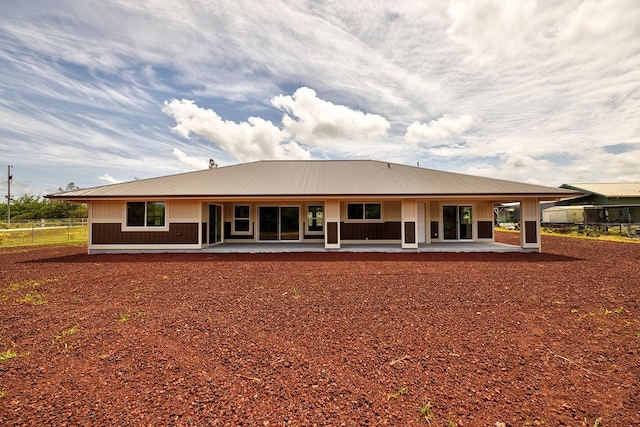 rear view of property with a patio, fence, and metal roof