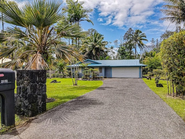 view of front of property featuring an attached garage, a front yard, asphalt driveway, and metal roof