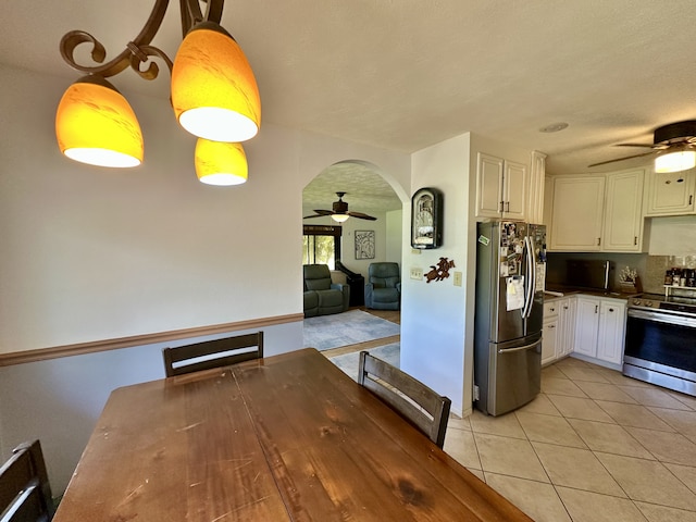 kitchen featuring stainless steel appliances, ceiling fan, dark countertops, light tile patterned flooring, and white cabinets