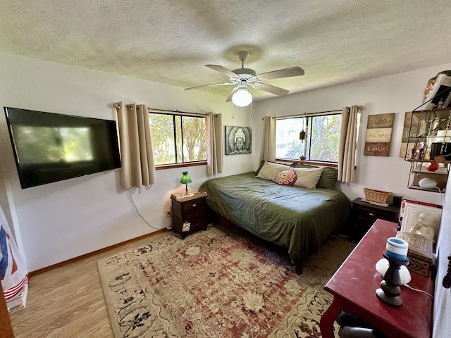 bedroom featuring a textured ceiling, wood finished floors, a ceiling fan, and baseboards