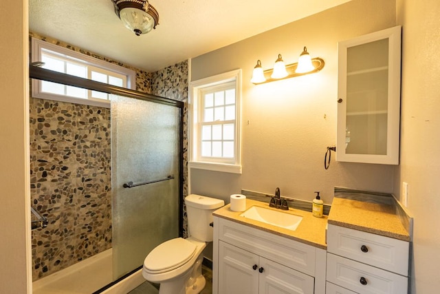 bathroom featuring vanity, plenty of natural light, toilet, and a stall shower