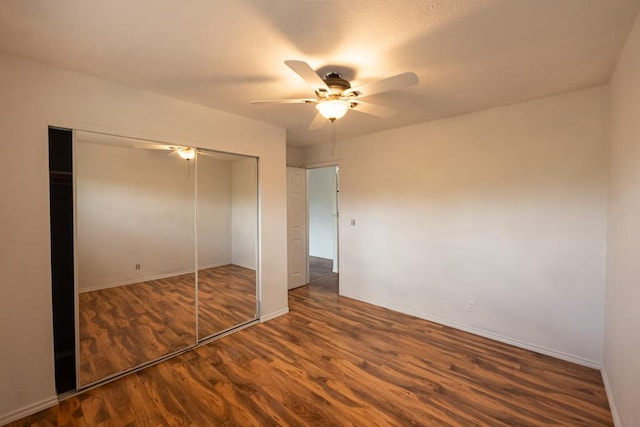 unfurnished bedroom with a closet, a ceiling fan, wood finished floors, and baseboards