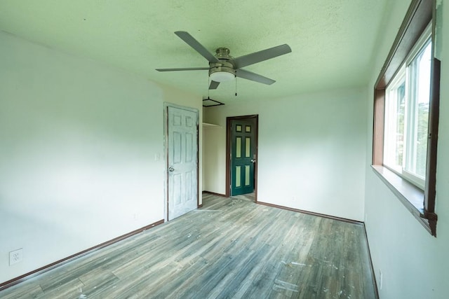 unfurnished room with a textured ceiling, baseboards, wood finished floors, and a ceiling fan