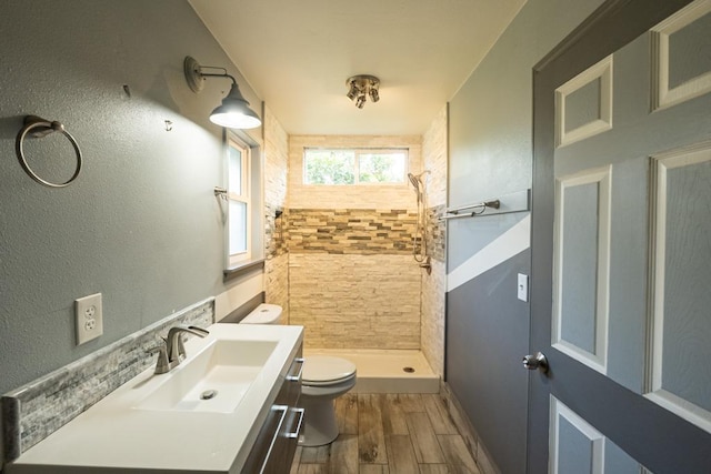 bathroom featuring toilet, vanity, wood finished floors, and a stall shower