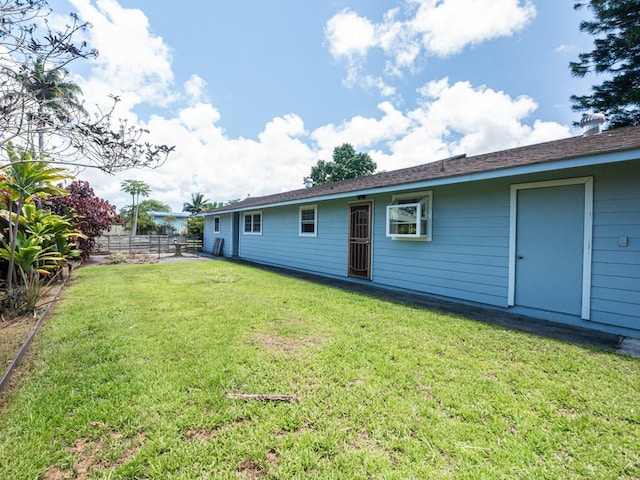 back of property featuring fence and a lawn