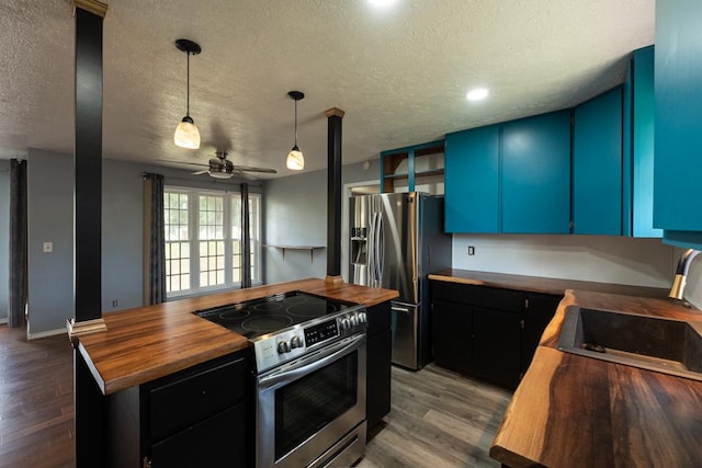 kitchen with wood counters, a textured ceiling, stainless steel appliances, and dark wood-style floors
