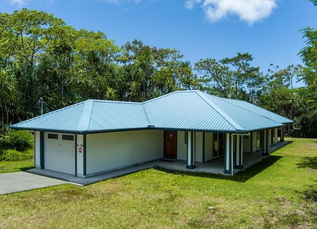 view of front of property featuring a front yard, metal roof, and driveway
