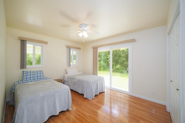 bedroom featuring access to outside, light wood-style flooring, baseboards, a ceiling fan, and a closet