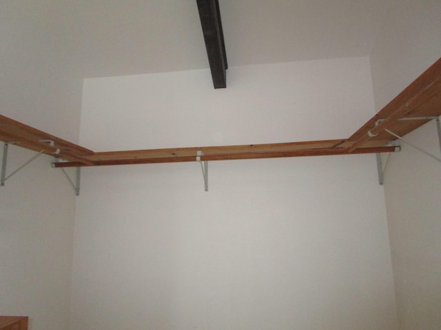 walk in closet featuring beamed ceiling