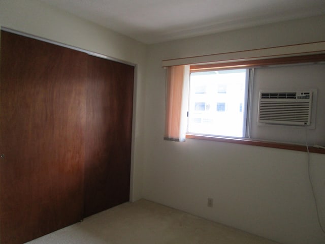 unfurnished bedroom with a wall unit AC, a closet, and carpet flooring