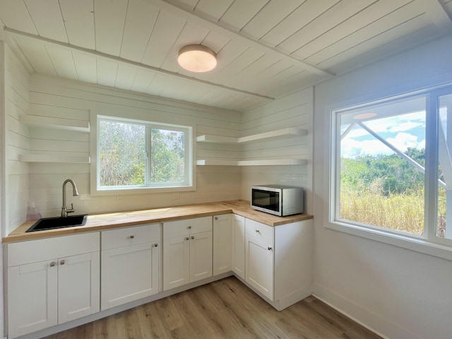 kitchen with open shelves, wood ceiling, stainless steel microwave, a sink, and wood counters