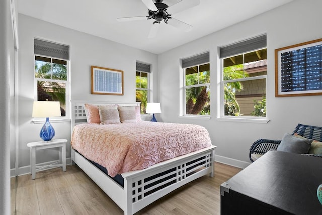 bedroom featuring baseboards, multiple windows, and light wood finished floors