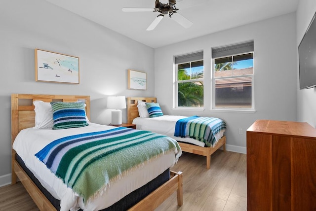 bedroom featuring light wood-style floors, a ceiling fan, and baseboards