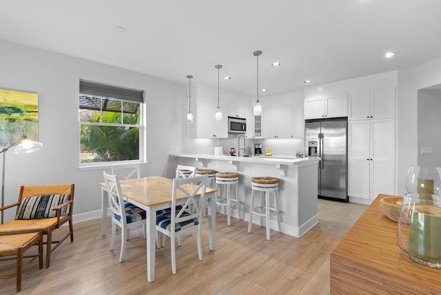 dining room with recessed lighting, baseboards, and light wood-style flooring