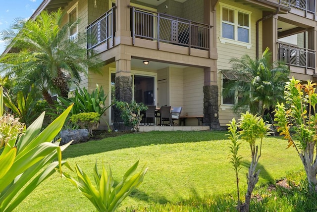 back of property with a yard and a balcony