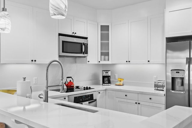 kitchen featuring light stone countertops, stainless steel appliances, and white cabinetry