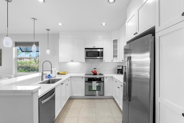 kitchen featuring a peninsula, appliances with stainless steel finishes, white cabinetry, and a sink