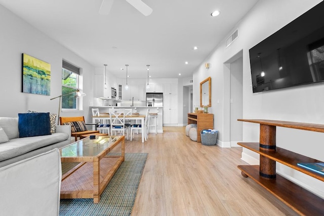 living area with visible vents, light wood-style floors, baseboards, ceiling fan, and recessed lighting