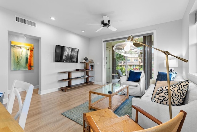 living area with baseboards, a ceiling fan, light wood-style flooring, and visible vents