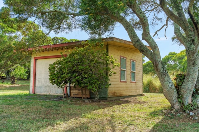 view of home's exterior featuring a garage, an outbuilding, and a lawn