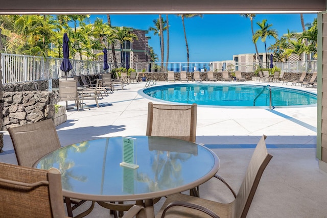 community pool featuring fence, a patio, and outdoor dining area